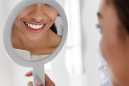 woman looking at veneers in mirror